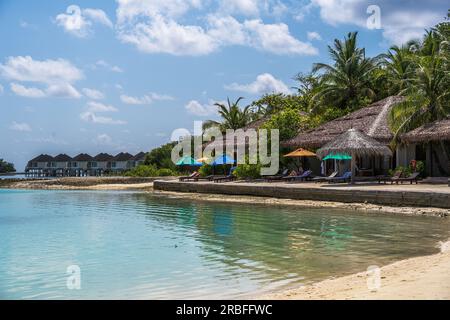 Malé, Maldives -- April 8, 2023. A colorful landscape photo of thatched huts on a beach in the Maldives Stock Photo
