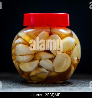 Sliced garlic cloves in honey in glass jar, close up. Honey infused garlic Stock Photo