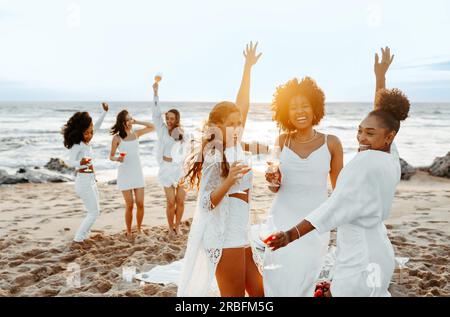 Group of diverse female friends dancing outdoors, having hen party celebration and enjoying great time by seashore Stock Photo