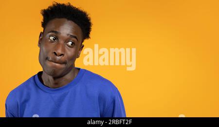 Desirous african american guy looking at copy space, yellow background Stock Photo