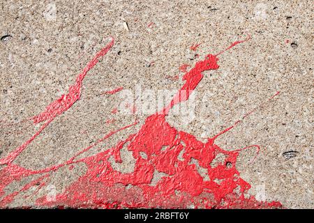 Background of very textured concrete with red paint spilled and splattered across it - grunge Stock Photo
