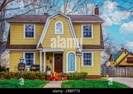 Beautiful yellow house with picturesque roofline and window with childs toy car parked in front - Curb appeal Stock Photo