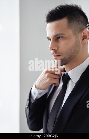 Young handsome man in elegant suit adjust his necktie on white background Stock Photo