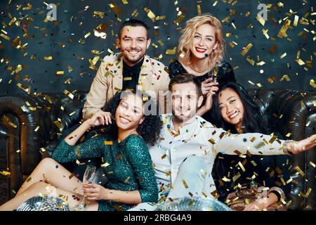 Diverse group of happy smiling friends having fun and enjoy party under confetti rain. New year, Birthday, celebration concept Stock Photo