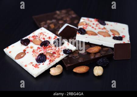 White and dark chocolate with dried raisins, coffee beans and nuts. Tasty dessert on dark wooden table Stock Photo