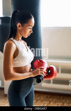 Sporty tired woman wearing boxing gloves posing in gym. Sport concept Stock Photo