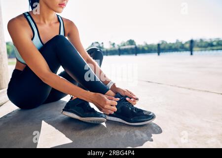 Young fitness woman runner tying shoe laces outdoors getting ready for jogging Stock Photo