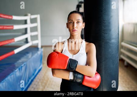 Sporty young woman wearing boxing gloves posing in gym. Sport concept Stock Photo