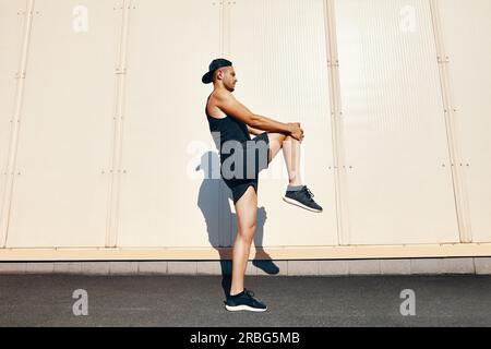 Sporty athlete man doing warm up and stretch legs outdoors Stock Photo