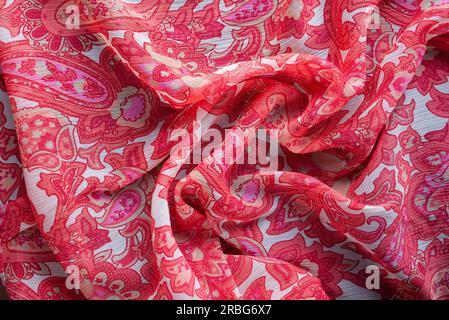 Soft folds of a pink synthetic fabric texture with an antique floral ornaments to be used as background Stock Photo