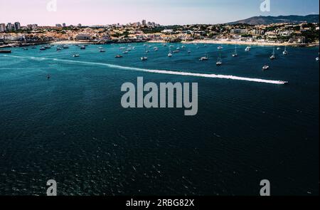Drone aerial view of beaches in Cascais, Portugal with fast moving boat on foreground leaving a wake Stock Photo