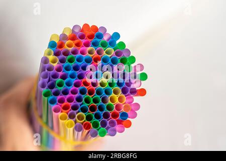 a lot of bright multicolored cocktail tubes are clutched in the bartender's hand. Multicolored Plastic Cocktail Tubes Stock Photo