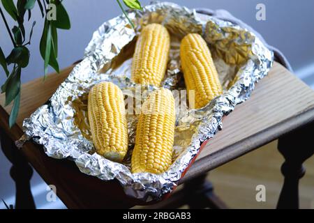 Raw corn on cobs in a baking dish. Prepare corn before cooking. Vegetable season. Fresh corn cobs prepared for cooking baked corn. Healthy eating. Veg Stock Photo