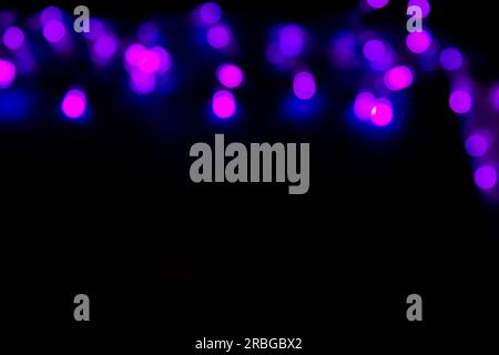 Purple Festive Christmas abstract bokeh lights on dark background with copy space for text or design. Abstract background with purple bokeh. Stock Photo