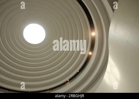 Illuminated circular skylight seen from below, concentric circles, modern white architecture, circular and organic forms. Interior image of a museum w Stock Photo