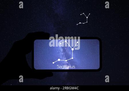 Man using stargazing app on his phone at night, closeup. Identified stick figure pattern of Sagittarius (Archer) constellation on device screen Stock Photo