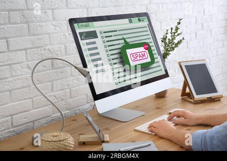 Spam warning message. Man using email software on computer at office desk, closeup Stock Photo