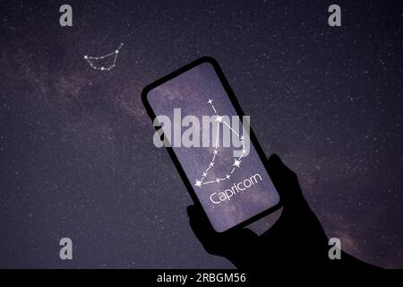 Man using stargazing app on his phone at night, closeup. Identified stick figure pattern of Capricornus (Capricorn) constellation on device screen Stock Photo
