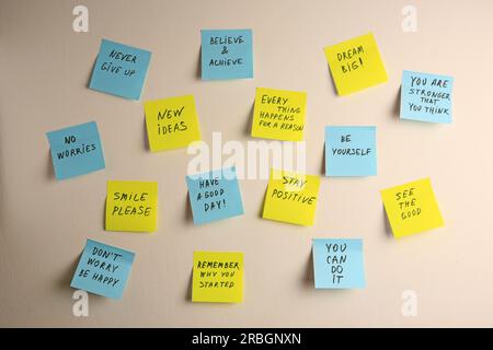 Paper notes with life-affirming phrases on white wall Stock Photo