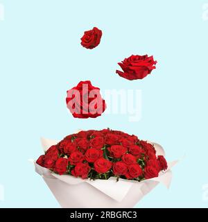 Flower buds flying into bunch of red roses on light blue background. Beautiful bouquet Stock Photo