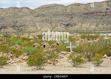 Grave sites in 1902 Terlingua cemetery outside the ghost town that was the Chisos Mining Company with eroding mesa ridge behind Stock Photo