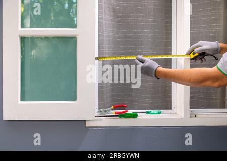 Man measuring wooden window frame for installation net screen insect. Stock Photo