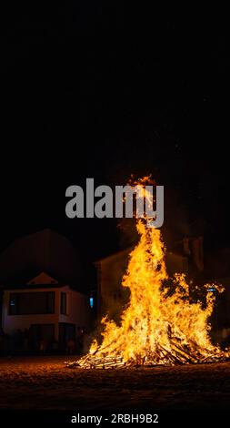 rural celebration with the hole town watching the fire of a bonfire at the beach at night with copy speace Stock Photo