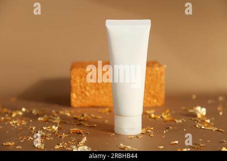 Mockup of white squeeze bottle cream tube for branding of medicine or cosmetics - cream, gel, skin care. Cosmetic bottle container, gold rectangular p Stock Photo