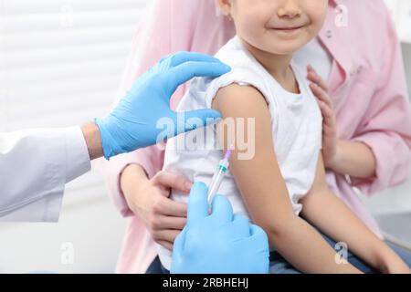 Children's hepatitis vaccination. Mother with her daughter in clinic. Doctor giving injection to little girl, closeup Stock Photo