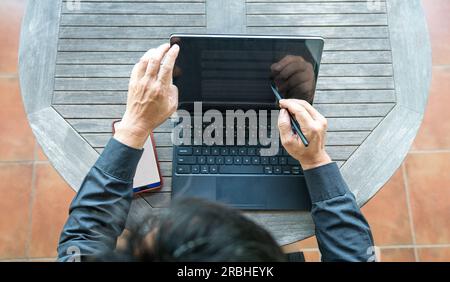 Businessman working on his tablet, using stylus pen and keyboard. Top view. Stock Photo