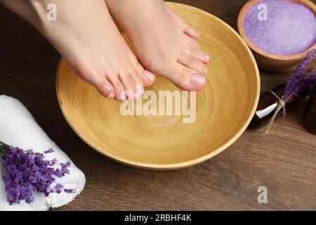 Woman soaking her feet in bowl with water, closeup. Pedicure procedure Stock Photo