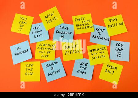 Paper notes with life-affirming phrases on orange background Stock Photo