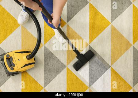 Woman hoovering carpet with vacuum cleaner, top view. Clean trace on dirty surface Stock Photo