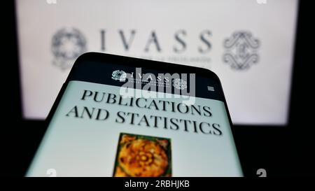 Mobile phone with website of Italian insurance supervisory authority IVASS on screen in front of logo. Focus on top-left of phone display. Stock Photo