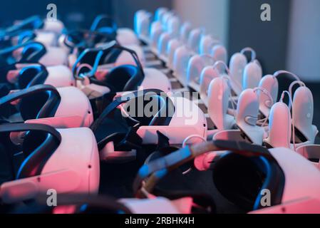 Virtual reality VR equipment on a table. VR headsets and joysticks. Neon lights Stock Photo