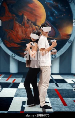 A couple wearing virtual reality VR equipment on an arena. A team using vr headsets and joysticks Stock Photo