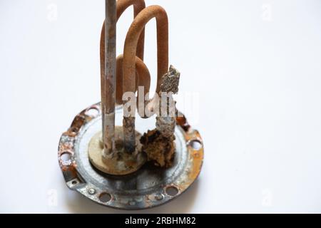 heating ten from a water heater after 8 years of operation broken on a white background, replacing an old ten from a boiler, repairing a broken part Stock Photo