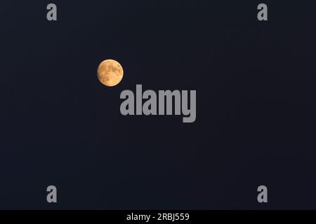 view on yellow waxing gibbous Moon in night sky Stock Photo