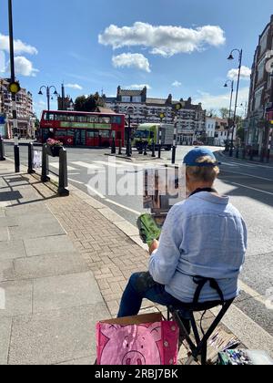 a man sitting on a collapsible chair does a painting of muswell hill broadway in watercolours N10 london england UK Stock Photo
