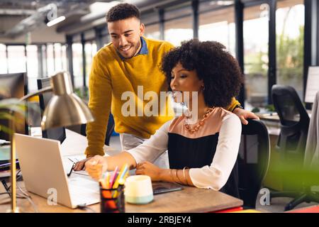 Diverse business people discussing work and using laptop at office. Business, teamwork, communication and work. Stock Photo