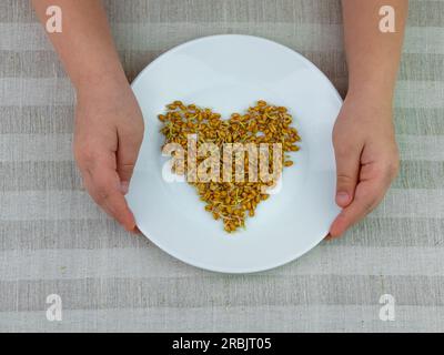 Sprouted wheat in child's hands on linen background. Macrobiotic food sprouts vegetarian meal. Healthy diet concept. Home growing plants in spring. Fr Stock Photo