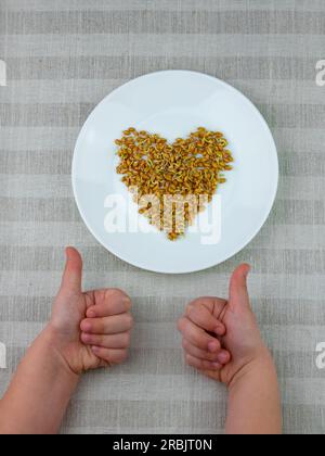 Sprouted wheat in child's hands on linen background. Macrobiotic food sprouts vegetarian meal. Healthy diet concept. Home growing plants in spring. Fr Stock Photo