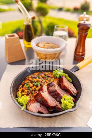 Bean stew with smoked and roasted pork hock slice on restaurant table Stock Photo