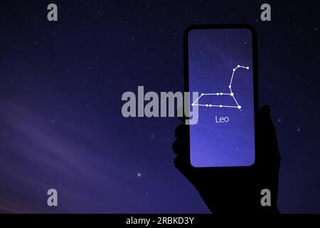 Woman using stargazing app on her phone at night, closeup. Identified stick figure pattern of Lion (Leo) constellation on device screen Stock Photo