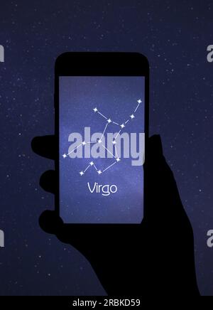 Woman using stargazing app on her phone at night, closeup. Identified stick figure pattern of Virgo constellation on device screen Stock Photo