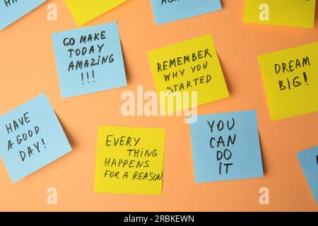 Paper notes with life-affirming phrases on pale orange background Stock Photo