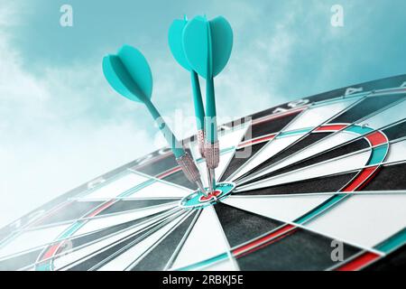 Dart board with turquoise arrows hitting target against sky Stock Photo