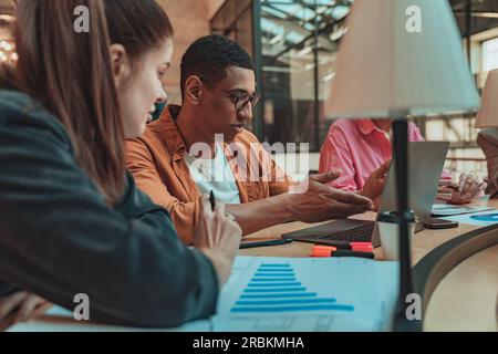 Focused business colleagues working with financial statements and use laptop in modern coworking Stock Photo
