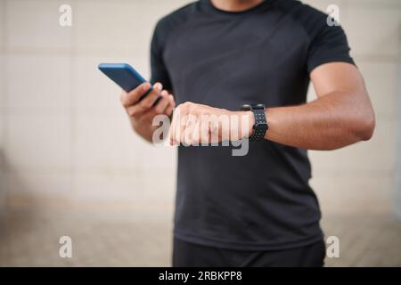 Sportsman checking notifications on smartwatch and smartphone after workout Stock Photo