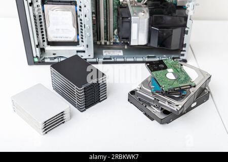 Closed-up view of hard disk drives with a PC in the background. Upgrade, repair and data recovery concept Stock Photo